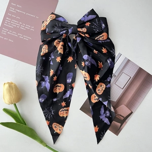 Detail of Halloween bow hair clip with pumpkin and spider web prints on satin fabric