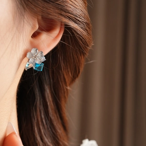 Macro detail of model wearing blue gemstone flower earrings with crystal accents