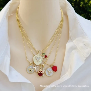 Dettaglio di collana a strati dorata con ciondoli a cuore, croce e angioletto