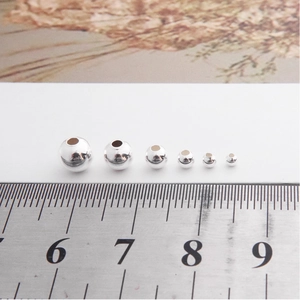 Macro shot of 925 silver beads in various sizes from 1mm to 5mm with a scale ruler