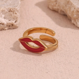 Close-up of a 18K gold plated lip-shaped open ring on a pink textured surface