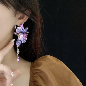 Close-up of purple flower drop earrings with crystals on a model with black background