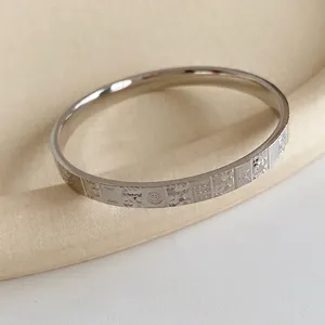 Minimalist silver metal cuff bracelet with embossed mahjong pattern and geometric engravings