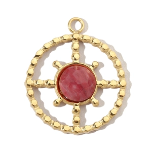 Detail of a golden round pendant with red stone and ship wheel design on white background