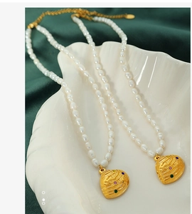 Macro view of freshwater pearl necklaces with irregular gold heart pendants on velvet