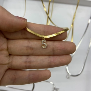 Close-up of gold snake chain necklace featuring a micro-paved zircon letter S pendant