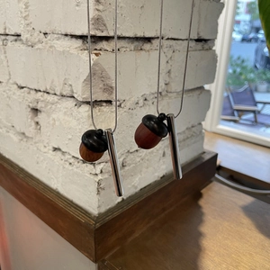 Detail of wooden acorn pendant with silver chain over a rustic white brick wall