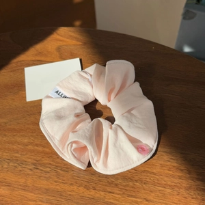 Detail of pink knit fabric hair scrunchie with a translucent flower-shaped button