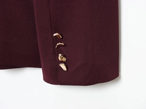 Detail of wine red suit sleeve with four golden irregular metal buttons on woven fabric