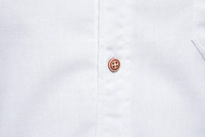 Detailed close-up of premium cotton fabric texture and brown buttons on white dress shirt