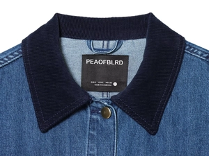 Dettaglio della giacca di jeans blu con colletto in velluto a coste e etichetta taglia