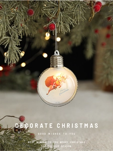 Detail of Christmas bulb ornament with Santa and reindeer hanging on a pine branch