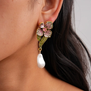 Detailed close-up of a floral pearl earring with colorful rhinestones on a model