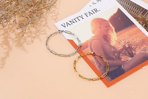Détail de bracelets en acier doré et argenté à maillons rectangulaires sur magazine