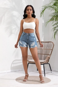 Macro detail of high-waisted frayed denim shorts in light blue with distressed ripped design