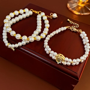 Detailed view of pearl bracelets with gold pendants on a dark mahogany jewelry box