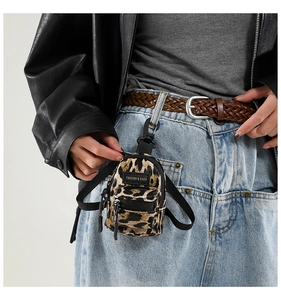 Close-up of mini leopard print bag with carabiner clip hanging on a belt loop