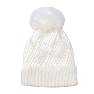 Close-up of white cable knit beanie with faux fur pom pom and ribbed cuff texture
