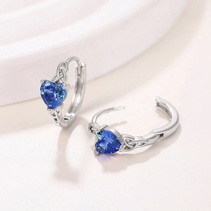 Detail of silver heart earrings with blue gemstone and Celtic knot design
