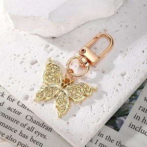 Macro shot of gold butterfly keychain with hollow patterns on textured white stone