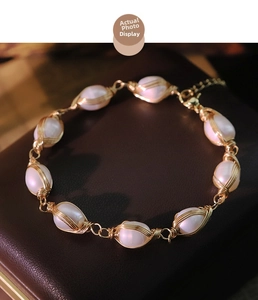 Detailed macro view of white oval pearls wrapped in gold wire with lobster clasp