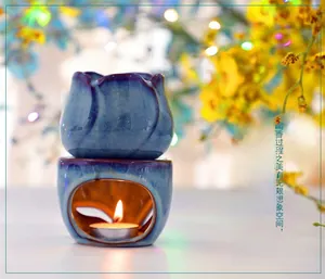 Blue tulip ceramic oil burner with cracked glaze and lit candle on floral background