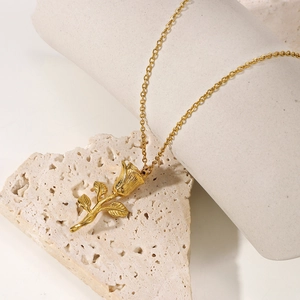 18K gold-plated 3D rose flower pendant necklace on white travertine and cylinder stands