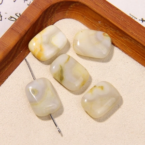 Detailed macro view of square natural agate beads with textures on a wooden tray