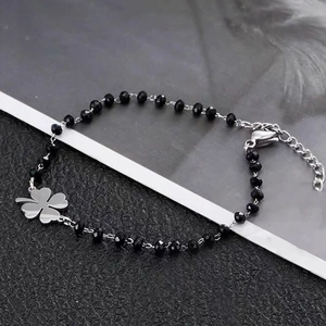 Macro shot of silver chain bracelet with black faceted beads and clover pendant