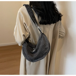 Detail of grey washed denim crescent bag styled with a cream trench coat for a casual look
