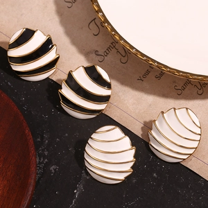Detail view of 18K gold plated oval earrings with black and white enamel sail stripes