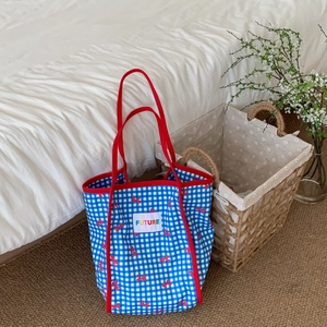 Detail of blue plaid tote bag with red bow prints and embroidered Future label