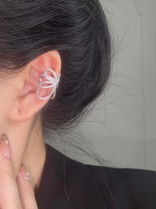 Detailed close-up of a silver butterfly ear cuff with sparkling zircon stones on a model