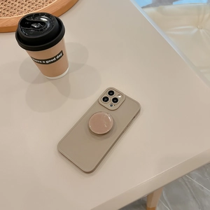 Detail view of khaki matte phone case with matching circular grip stand on a beige desk
