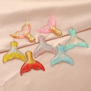 Detail view of seven gradient resin mermaid tail pendants with glitter and gold foil