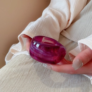 Macro detail of wide translucent dark purple resin bangle with white cloud patterns