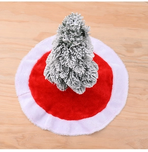 Close-up of red plush mini Christmas tree skirt with white border on wooden surface