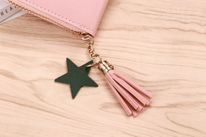 Detail of pink faux leather coin purse with green star charm, tassel and gold zipper