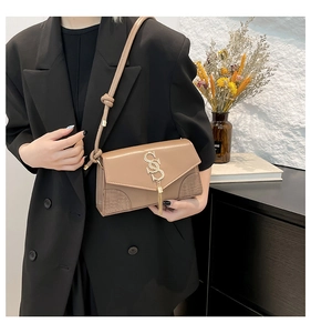 Detail of khaki crossbody bag featuring golden S-buckle and tassel on crocodile texture