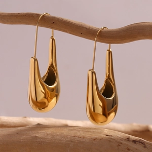 Boucles d'oreilles minimalistes dorées en forme de goutte irrégulière sur une branche