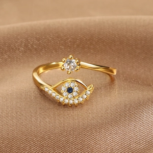 Adjustable gold evil eye ring with blue and white zircon on premium brown silk background