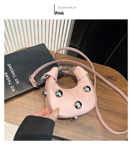 Detailed top view of pink mini dumpling bag with silver rivets on a wooden table