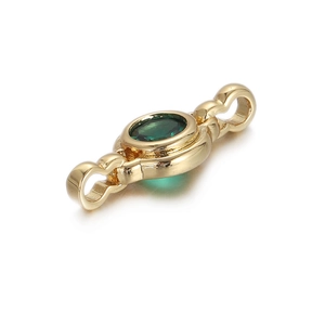 Macro shot of gold jewelry connector with green oval gemstone and circular zircon accents