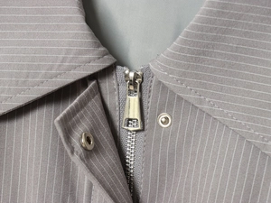 Macro shot of grey striped fabric texture with silver metal zipper and snap button detail