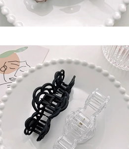Black and clear matte camellia hair claws in a decorative tray on a minimalist desk