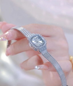Close-up of a silver square watch with rhinestone bezel and mesh strap on a woman's wrist
