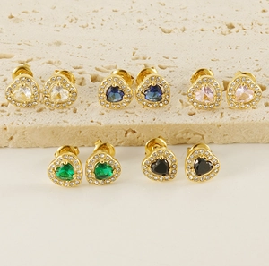 Détail de cinq boucles d'oreilles en cœur avec zircons colorés sur socle beige