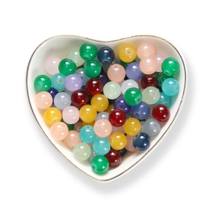 Mix di perline di vetro colorate in una ciotola di ceramica a forma di cuore per DIY