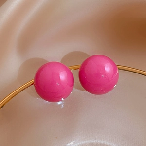 Macro view of bright magenta spherical studs with high-gloss finish and golden metal rings