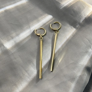 Minimalist gold geometric drop earrings on silver silk background for a premium look